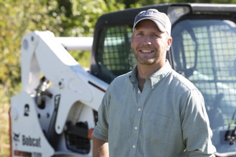 Chase Burns, owner of Dogwood Land Management standing next to his Bobcat T650 compact track loader