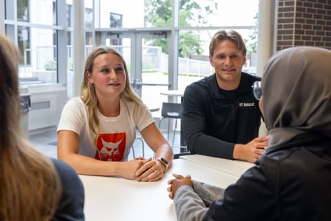 Bobcat Interns Have a Discussion at a Table