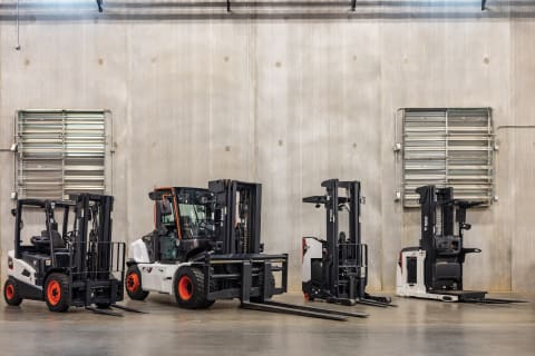 A lineup of four Bobcat forklifts shown in a warehouse setting.