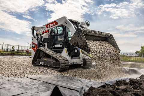 A Bobcat T86 Compact Track Loader Dumps a Bucketful of Rocks Onto Landscaping Fabric 