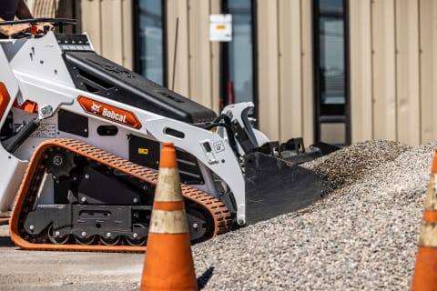 A Bobcat Mini Track Loader Lifts a Bucketful of Pea Rock With a Bucket