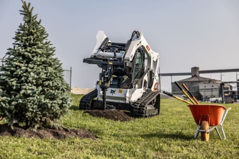 A Bobcat Compact Track Loader Digs a Hole for Tree Installation With the Auger Attachment