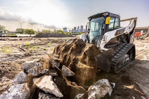 The Bobcat Platinum T76 compact track loader uses its bucket attachment to pick up material on the jobsite.