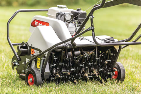 Close up of the tines on a Bobcat AE26 aerator as it moves across established turf 