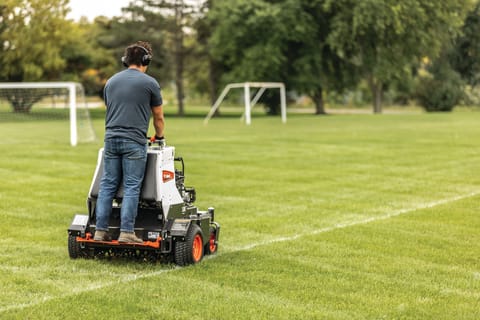 Operator uses a Bobcat AE30 aerator on a soccer field 