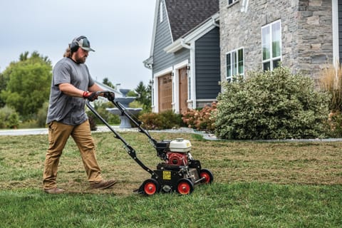 Operator uses a Bobcat DT18 dethatcher in the front yard of a residential property 