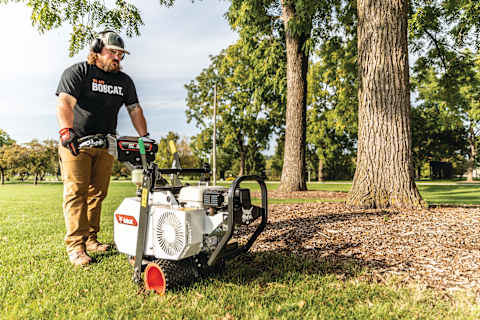A Bobcat SC18h Sod Cutter being used by an operator to cut sod around a tree for landscaping.