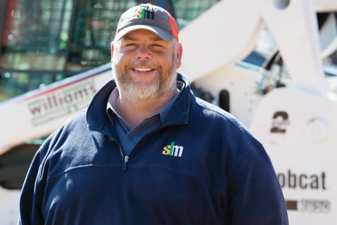 Bo Smith Standing in Front of a Bobcat Machine