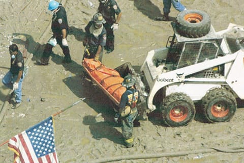 FDNY responders and a Bobcat 843 skid-steer loader recovering the body of a victim at ground zero.