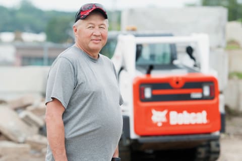 Jim Linhart stands next to his Bobcat T595 compact track loader.