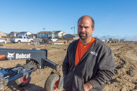 Mark Knorr stands next to a Bobcat grader attachment on a jobsite.