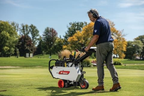 Operator uses a Bobcat SC12 to cut sod near a putting green at a golf course