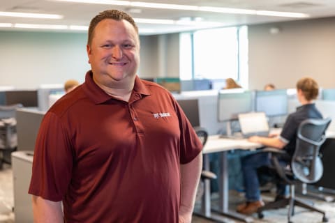 A Bobcat Employee Smiles as He Stands in an Office Space