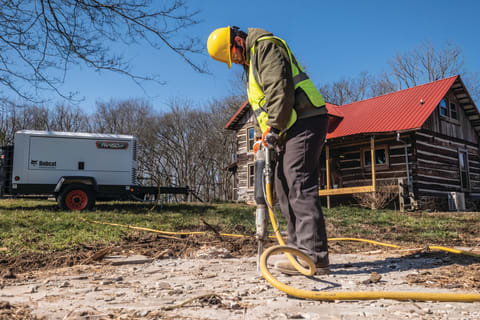  Man Uses a Hand-Held Breaker Tool Powered by a PA450VP Air Compressor
