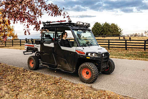 A Bobcat UV34XL UTV Travels Along a Gravel Road on an Acreage