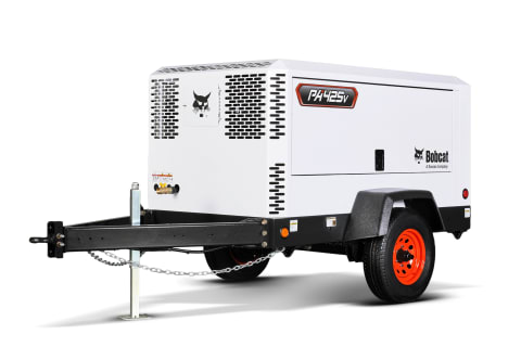 A Bobcat Portable Air Compressor positioned outdoors and secured with wheel chocks. 