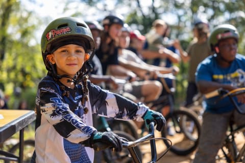 Children on BMX Bikes Line Up on a Dirt Track Built by Bobcat and RADshare