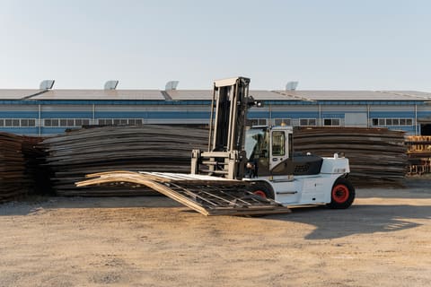 A Bobcat DV180S-7 Forklift Lifts a Heavy Load of Steel Material on an Outdoor Jobsite