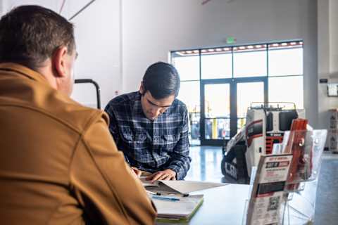 Two people reviewing printed materials at a counter inside a Bobcat dealership 