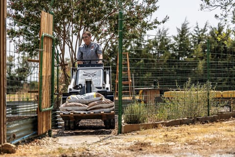 A Bobcat MT100 Mini Track Loader Operator Maneuvers the Machine Through a Fence Opening