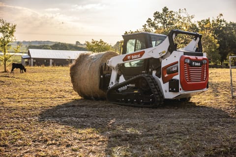 Bobcat T66 Compact Track Loader Using Bale Fork to Place Hay for Cow in Field