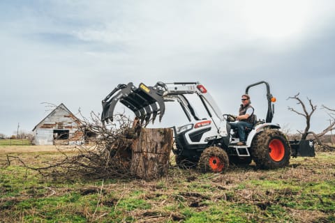 Chip Gaines uses a CT2025 Bobcat Compact Tractor with a grapple attachment to move tree brush.