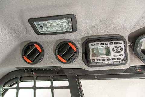 Close-up of overhead air vents and heavy-duty control panel in a Bobcat loader cab, showcasing heating and air conditioning features.