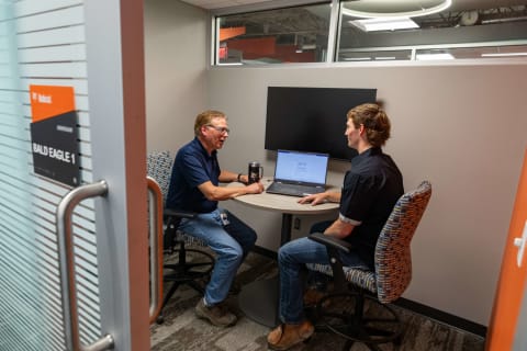 Dos empleados de Bobcat conversan sobre trabajo en un espacio de reuniones