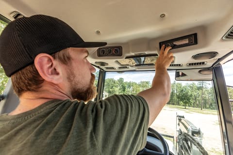 Operator Adjusts the Radio Inside the Cab of a Bobcat UT6573 Utility Tractor