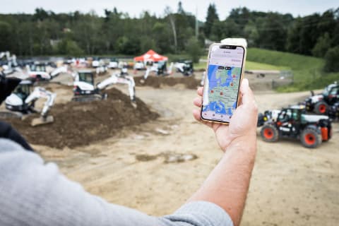 Een man die de Bobcat Machine IQ-app gebruikt om zijn E50z-minigraafmachine te controleren.