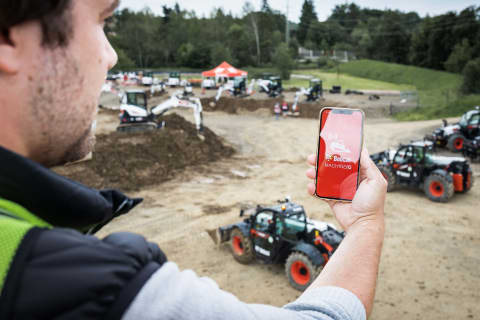 Operatore che controlla un miniescavatore E50z con l'app Bobcat Machine IQ.