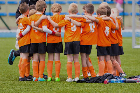 A Youth Soccer Team Dressed in Bobcat Orange Uniforms Forms a Huddle