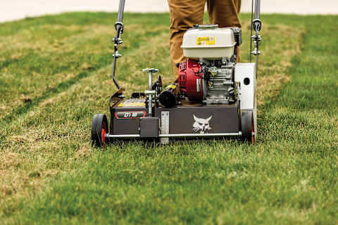 Close up view of a Bobcat DT18 dethatcher as it works in the front yard of a residence