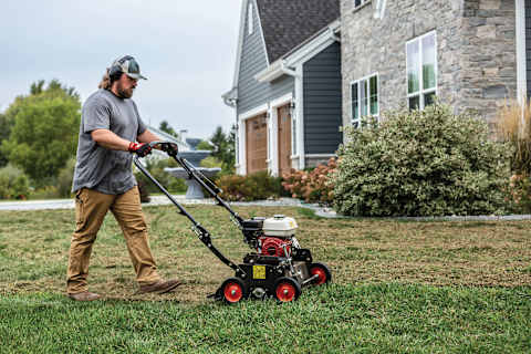 Operator uses a Bobcat DT18 dethatcher in the front yard of a residential property 