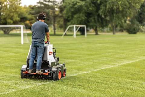 Operator uses a Bobcat AE30 aerator on a soccer field 