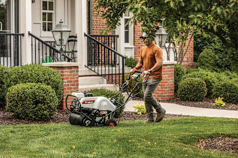 Man Aerates Residential Lawn Using a Bobcat AE19