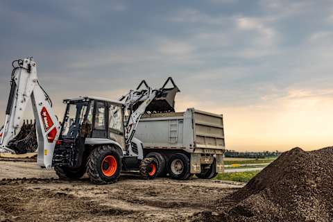  A Low View of the Bobcat B760 Using Its Bucket to Dump Dirt Into a Dump Truck