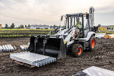 A Bobcat B760 Backhoe Loader Carries a Pallet of Materials at the Front of the Machine