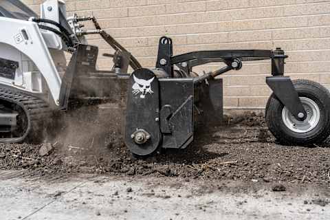 Extreme close up shot of the Bobcat soil conditioner attachment on a Bobcat MT120 mini track loader working on a construction jobsite