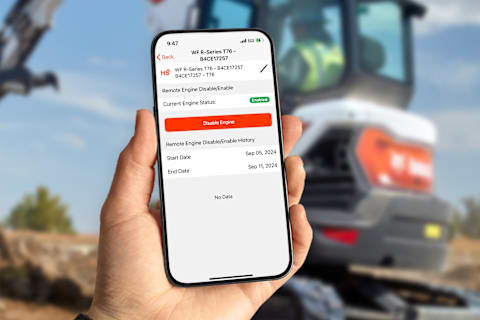 A person holds a phone displaying the Bobcat Machine IQ Remote Engine Disable/Enable screen
