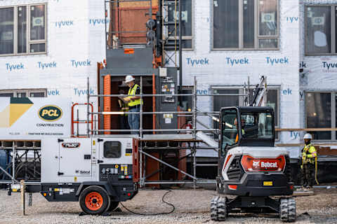 Bobcat compact excavator and generator powering a commercial construction site, showcasing equipment eligible for Section 179 tax deductions for small businesses.