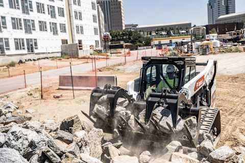 On a Demolition Jobsite, a Bobcat T86 Compact Track Loader Closes the Jaws of a Grapple Attachment Around a Load of Concrete Rubble