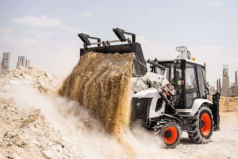 Bobcat B730 backhoe loader dumping a pile of dirt at an outdoor construction site in Dubai.