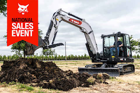 A Bobcat E88 Compact Excavator With a Bucket Digs a Hole in the Soil; the National Sales Event Banner Is on the Top-Left Corner