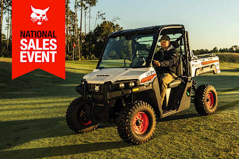A Man Drives a Bobcat UV34 Utility Vehicle Across a Perfectly Manicured Golf Course 