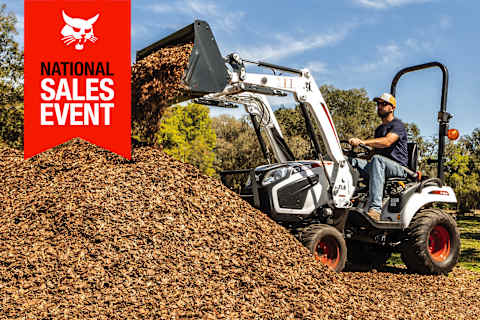 A CT1025 Compact Tractor Dumps Mulch Onto a Pile Using Its Bucket