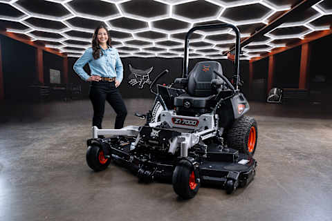 Hero 3/4 left front shot of a Bobcat ZT7000 zero-turn riding mower in studio environment with female Bobcat host standing with hands on hips