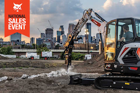 An Urban Jobsite With a Bobcat Portable Generator, Portable Air Compressor and Portable Light Tower. A Bobcat Compact Excavator Works in the Foreground With the National Sales Event Badge.