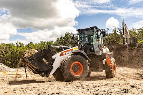 Bobcat L235 wheel loader moving soil with Bobcat excavator in background at construction site