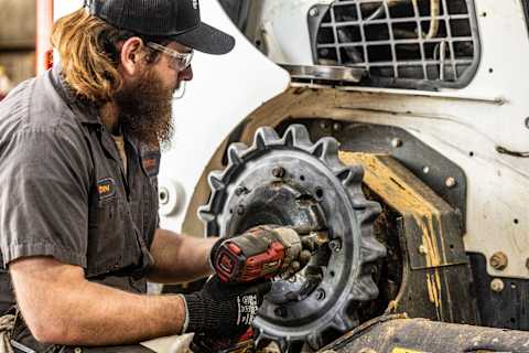 Bobcat technician working on drive motor of compact loader
